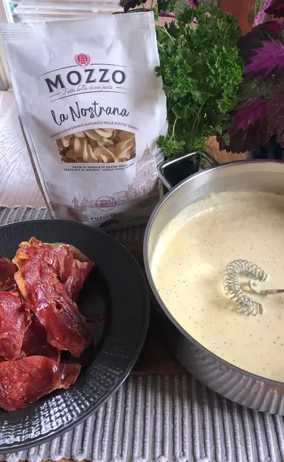 Pasta med ostsås toppad med knaprig serranoskinka.